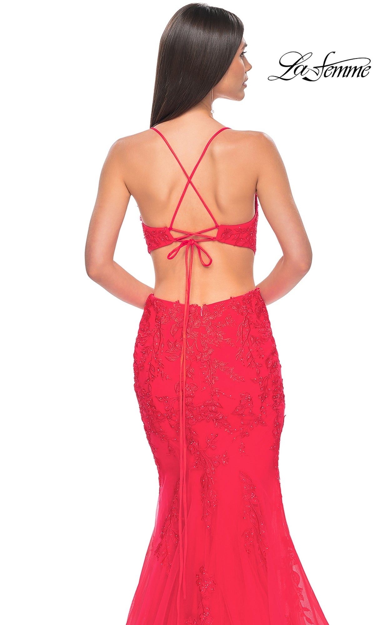 A woman models the La Femme Long Lace Mermaid Prom Dress 31133, featuring thin crisscross straps and elegant lace detailing, set against a white background with the